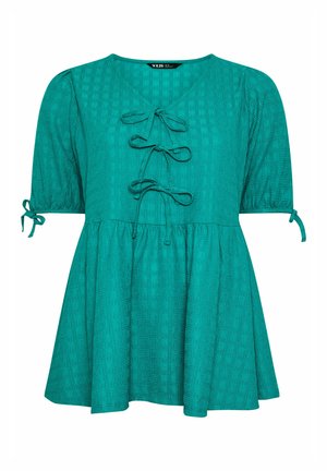 Türkisfarbene kurzärmelige Bluse aus strukturiertem Stoff mit drei vorderen Schleifen, geraffter Taille und Schleifen an den Ärmeln vor weißem Hintergrund.