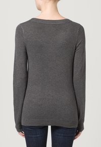Grijze trui met lange mouwen, geribbelde halslijn en onderrand. Gemaakt van een zachte stof, met een losse fit en minimale details.