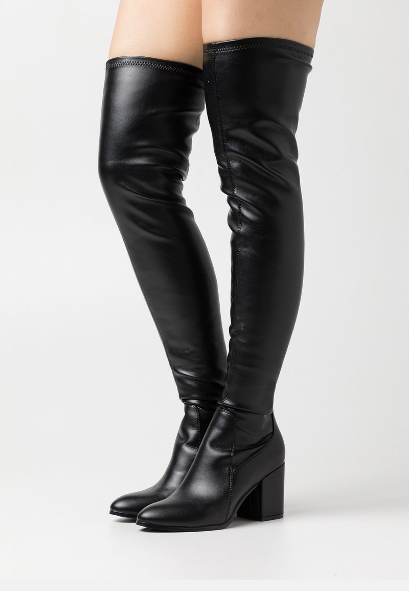 Botas de cuero negro hasta la rodilla con un diseño elegante, tacones cuadrados y textura suave que presenta costuras visibles a lo largo de la parte superior.
