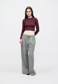Top corto de manga larga color granate con un pequeño logo; pantalones de pierna ancha color gris claro con cintura ajustable con cordón. Tela suave con un corte relajado.