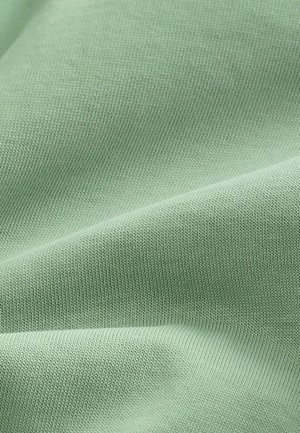 Ljust grönt bomullstyg med en fin ribbad textur, som visar släta veck och en subtil lyster. Idealisk för kläder och mjuka produkter.