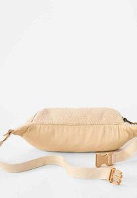 Beige taske med en struktureret fleece top og en glat stofbund. Har en lynlåslukning og justerbar klipsrem.