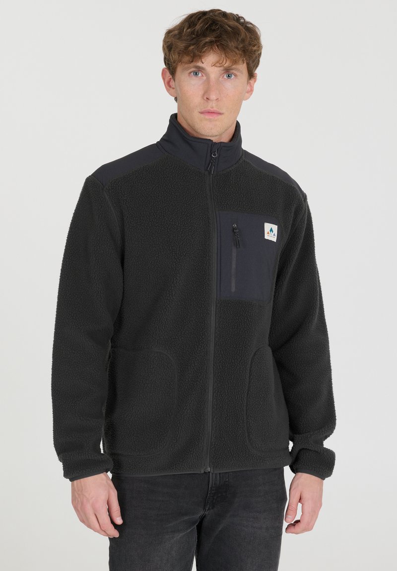 Veste en polaire gris foncé avec un col haut, poche zippée sur la poitrine et deux poches avant. Texture douce et design décontracté.