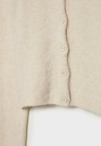 Lys beige cardigan, blød tekstur, med seks matchende knapper langs kanten, har en lidt løs pasform og ribbet kant.