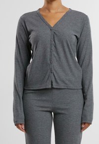 Šedý pletený set domácího oblečení obsahující top s dlouhým rukávem a výstřihem do V s knoflíky a odpovídající kalhoty, které se vyznačují měkkou texturou a přiléhavým střihem.