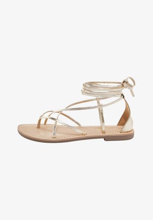 Sandalias planas metálicas doradas con múltiples diseños de tiras, tobillo envolvente, una suela beige y una plantilla de cuero suave. Acolchadas para mayor comodidad.