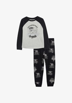 Chemise grise à manches longues avec des manches raglan noires présentant un graphique de super-héros ; pantalon noir avec un imprimé de super-héros blanc et des chevilles resserrées.