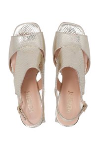 Metallisch goldene Sandalen mit Reptilstruktur, offener Zehenpartie und ausgeschnittenen Seiten. Mit einem verstellbaren Knöchelriemen und einem leichten Design.