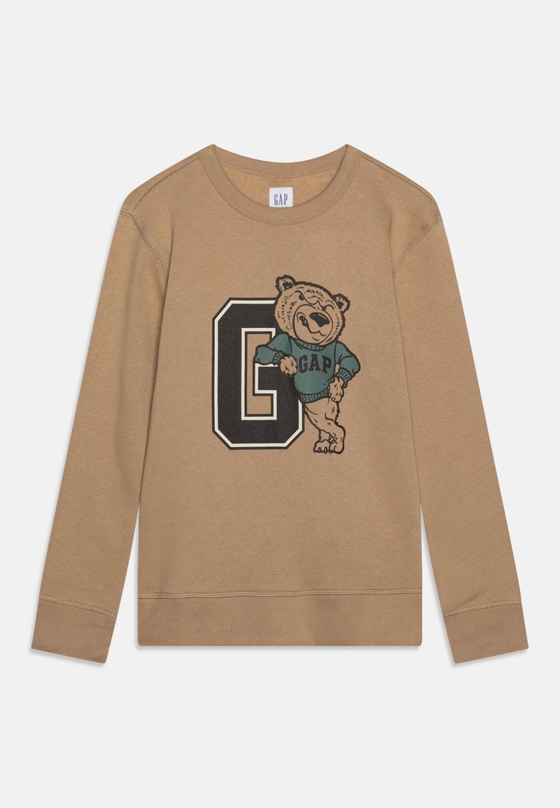 Sweat-shirt à manches longues marron clair avec un grand "G" noir et un ours souriant portant un sweat GAP bleu appuyé sur la lettre.