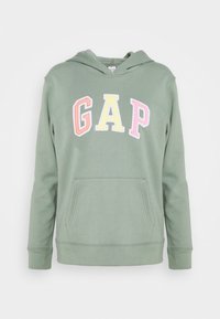 Sudadera verde con bolsillo frontal tipo canguro. Presenta el logo "GAP" bordado multicolor en tonos pastel en el pecho. Textura de tela suave.