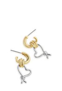 Guld- og sølvøreringe har buede løkker med en hjerteform, der viser et snoet design og en poleret overflade.