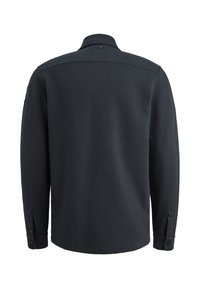 Temno modra majica s dolgimi rokavi iz teksturirane waffle pletenine. Ima stoječ ovratnik in gumbe na manšetah. Enostaven dizajn, brez vzorcev.