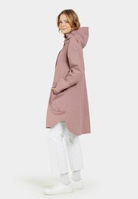 Lång, något överdimensionerad rosa regnjacka med huva, med en böjd nederkant, två framfickor och tryckknappsdetaljer.