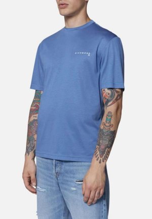 T-shirt in cotone blu con scollo rotondo e logo bianco "Richmond" sul petto. Abbinato a jeans chiari strappati.