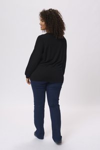 Pull noir côtelé à manches longues, associé à un jean droit bleu foncé. La texture est lisse, avec une coupe décontractée.