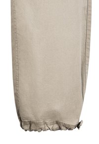 Beige Hose mit gerafftem Saum, glattem Stoff und sichtbaren Nähten an den Seiten. Keine Muster oder zusätzlichen Details vorhanden.