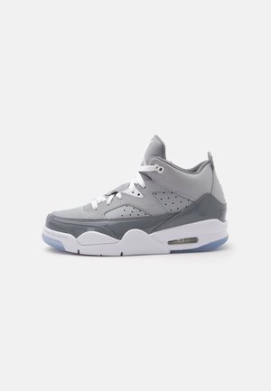 Chaussure de sport montante grise et blanche avec des lacets blancs, des panneaux latéraux perforés et un coussin d'air visible dans la semelle.