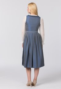 Traditionelles blaues Kleid mit tailliertem Oberteil und gefälteltem Rock. Verfügt über lange Ärmel aus weißer Spitze und ein geflochtenes Dekolleté.