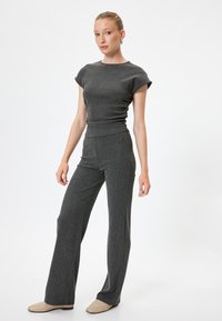 Grijze gebreide tweedelige outfit bestaande uit een aansluitend top met korte mouwen en hoge taille wijde broek met subtiele verticale textuur.