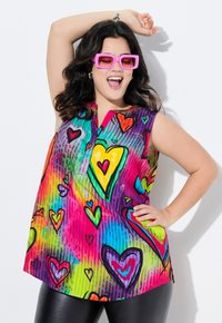 Tunic senza maniche colorata con un vivace motivo a cuore in diverse tonalità di rosa, viola, blu e verde. Realizzata in tessuto leggero.