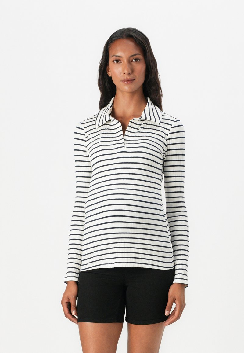 Långärmad polo i vitt med navy horisontella ränder, med klassisk krage och ribbad textur, parat med svarta shorts.