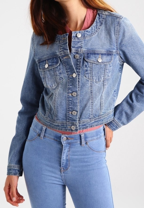 Bijgesneden spijkerjack, lichtblauw, met zilveren knopen, twee borstzakken en een ronde hals. Gedragen over een roze top en gecombineerd met een blauwe spijkerbroek.