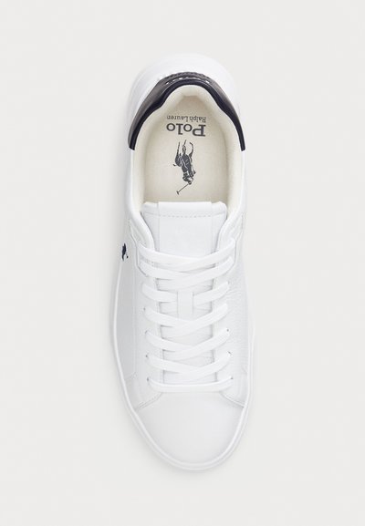 Hvite lær sneakers med snøring, kontrastfarget svart hælflik og preget logo på tungen. Glatt tekstur og minimalistisk stil.
