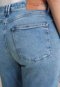 Jasnoniebieskie dżinsy z tylną kieszonką, subtelne przeszycie i skórzana metka na pasku z napisem "Marc O'Polo DENIM".