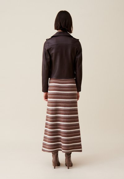 Veste de moto en cuir marron, jupe longue rayée marron et crème, bottines, texture lisse, design ajusté, détails de couture visibles.