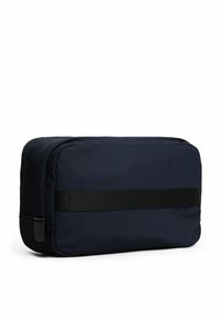 Borsa da toeletta in nylon blu marina con forma rettangolare, chiusura a zip e una tracolla in tessuto nero al centro. Texture liscia e design minimal.