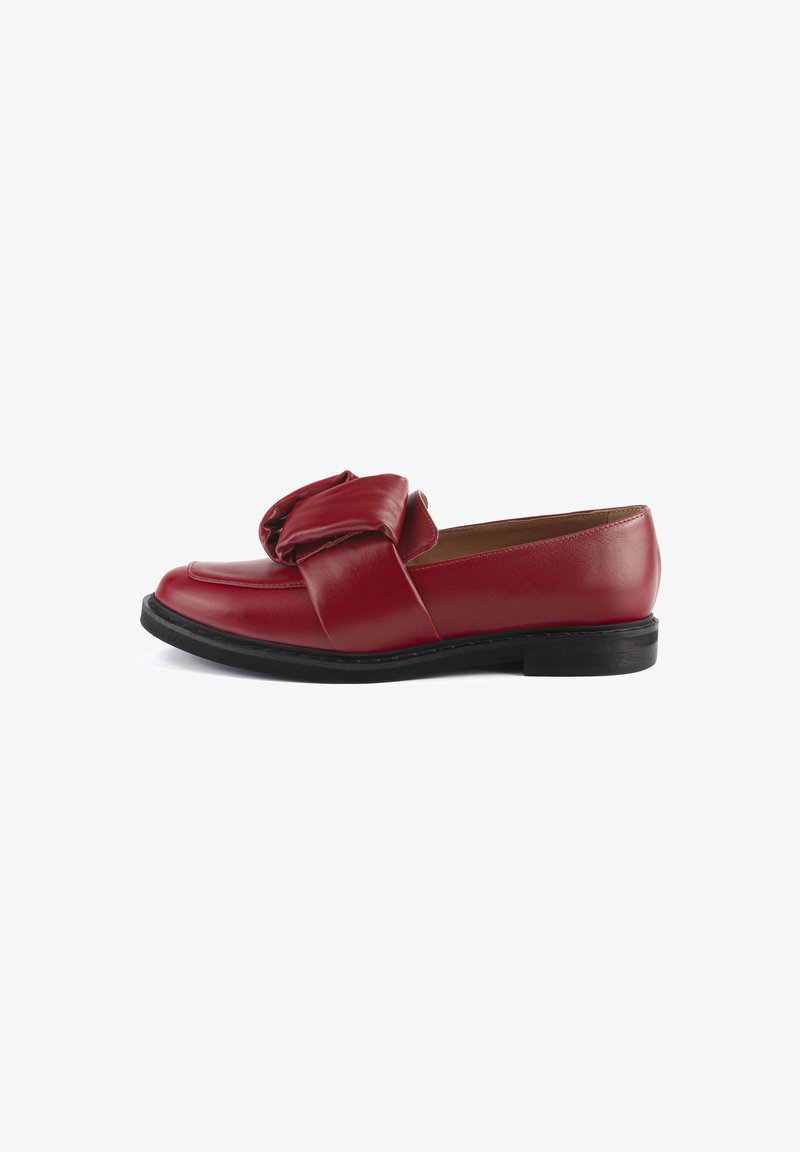 Mocassins en cuir rouge avec un détail de nœud proéminent à l'avant, semelle noire plate et texture lisse. La vue de côté dévoile un design épuré.