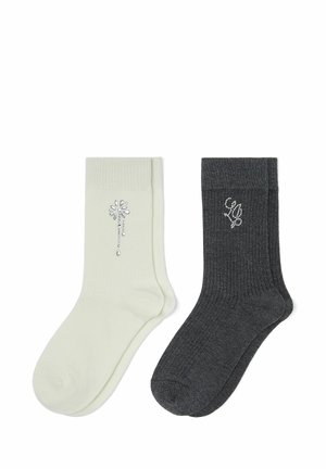 Un par de calcetines crema con un pequeño diseño floral de pedrería y un par de calcetines acanalados gris oscuro con un monograma de pedrería.