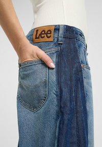 Jeans i denim med ljus tvätt och en mörkare panel, läderpatch med Lee-logotyp och sidofickdetaljer. Kännbart repat mönster på tyget.