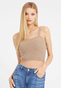Pūkuotukas, smėlinės spalvos, trumpas tank top'as su smulkiais petnešomis, tekstūruotas audinys, tiesi iškirptė ir neapdorotas galas, derinamas su mėlynomis džinsinėmis kelnėmis.