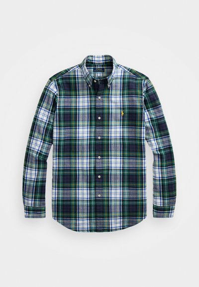 Grønn og marineblå rutete skjorte med lange ermer, spredt krage og hvite detaljer, med en liten brodert logo på brystet.