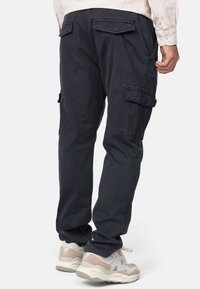 Navy cargobroeken van katoen met zijzakken, achterzakflappen en een losvallende pasvorm. Gecombineerd met lichte sneakers.