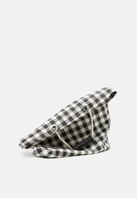 Černobílá kostkovaná látková taška s designem na překládání, vybavená stříbrnými očky a černou akcentovanou rukojetí. Texturovaný povrch.