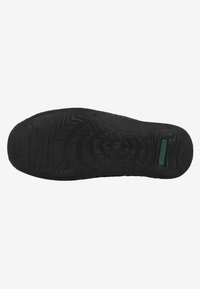 Suola di scarpa nera con un motivo di battistrada testurizzato per una migliore aderenza. Presenta un materiale liscio e flessibile e un'etichetta verde a contrasto.