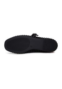 Suola di scarpe in gomma nera con una superficie testurizzata. Presenta piccoli punti rialzati per la presa e un pannello centrale liscio. Forma arrotondata.