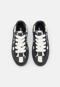 Schwarz-weiße karierte Canvas-Sneaker mit weißen Schnürsenkeln, einer gummierten schwarzen Sohle und einem gepolsterten Knöchel für Komfort.