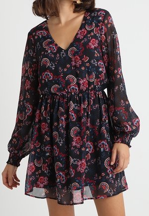 Robe mini florale en tissu transparent noir avec un décolleté en V, de longues manches bouffantes et une taille élastique. Présente des motifs paisley rouges et bleus.