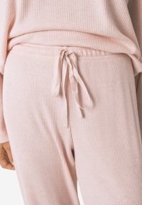 Lichtroze geribde loungebroeken met een trekkoord in de taille, met een zachte textuur en een subtiele glans in de stof.