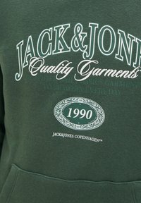 Haut à capuche en coton vert arborant le texte "JACK & JONES", le logo et l'année "1990" en blanc. Comprend une poche frontale avec une texture douce.