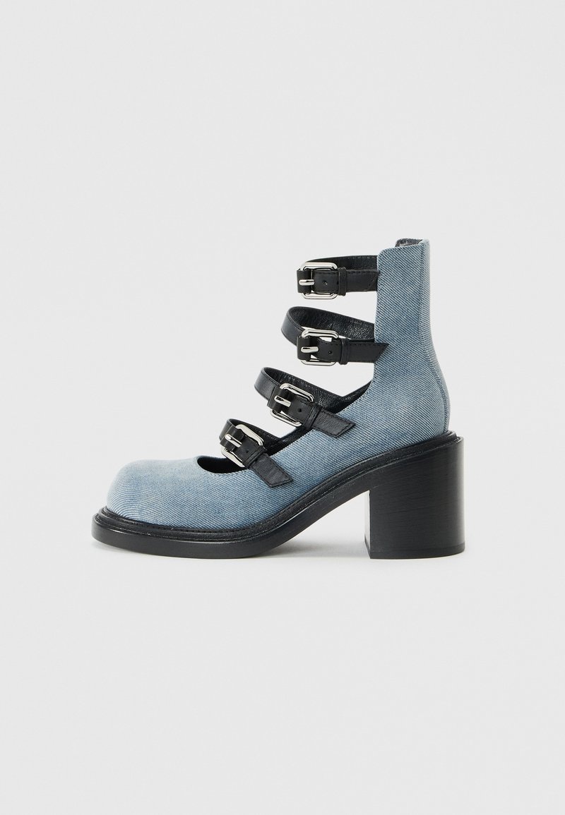Light blue denim ankle boot with a rounded toe, three black leather straps, and silver buckles. Features a chunky black heel.