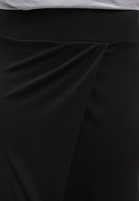 Czarna spódnica z szerokim pasem; posiada asymetryczne drapowanie z przodu; gładki, teksturowany materiał.