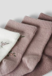 Drei Paar gestrickte Socken in Weiß und Nuancen von hellrosa. Ein Paar hat florale Stickerei. Strukturierter Stoff mit gerippten Bündchen.