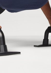Mangos de flexión negros con una base estable, que cuentan con un área de agarre texturizada y un diseño en ángulo para mejorar el rendimiento y la comodidad durante los entrenamientos.