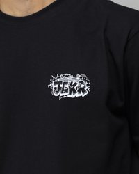 T-shirt di cotone nero con un logo in stile graffiti bianco con il testo "JEKR" sull'area sinistra del petto. Maniche corte e scollatura a girocollo.