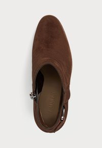 Stivaletto in suede marrone con punta appuntita, zip laterale e una fodera interna liscia con un sottile marchio sulla soletta.