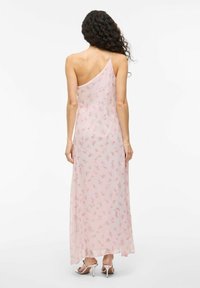 One-shoulder, pink floral chiffon dress. Long and flowing design with delicate rose patterns, sheer texture, and a soft, lightweight appearance.